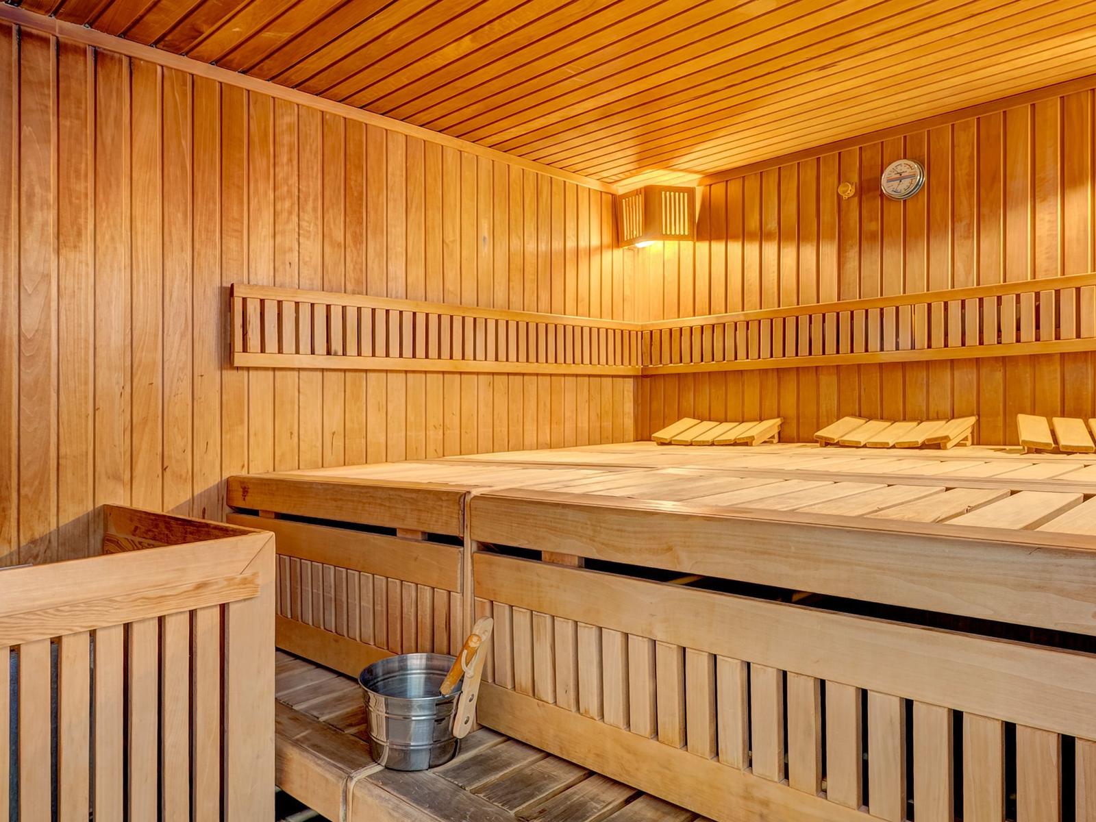 Sauna mit Holzbank, Thermometer und Eimer mit Besen