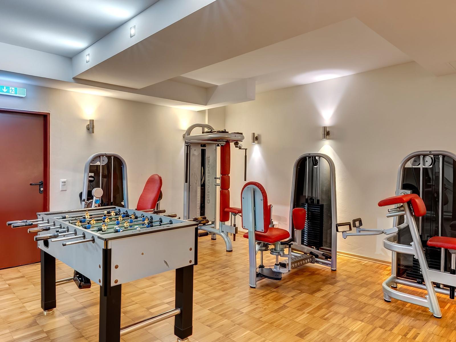 Fitnessraum mit Trainingsgeräten und Tischfußball.