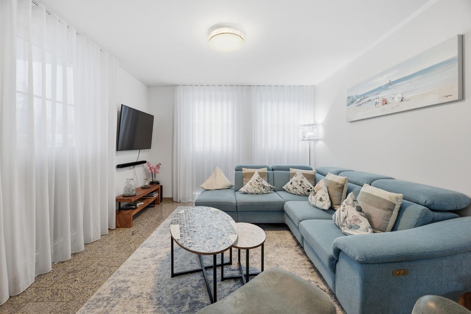Wohnzimmer mit blauem Sofa, Couchtisch und Wandbild.