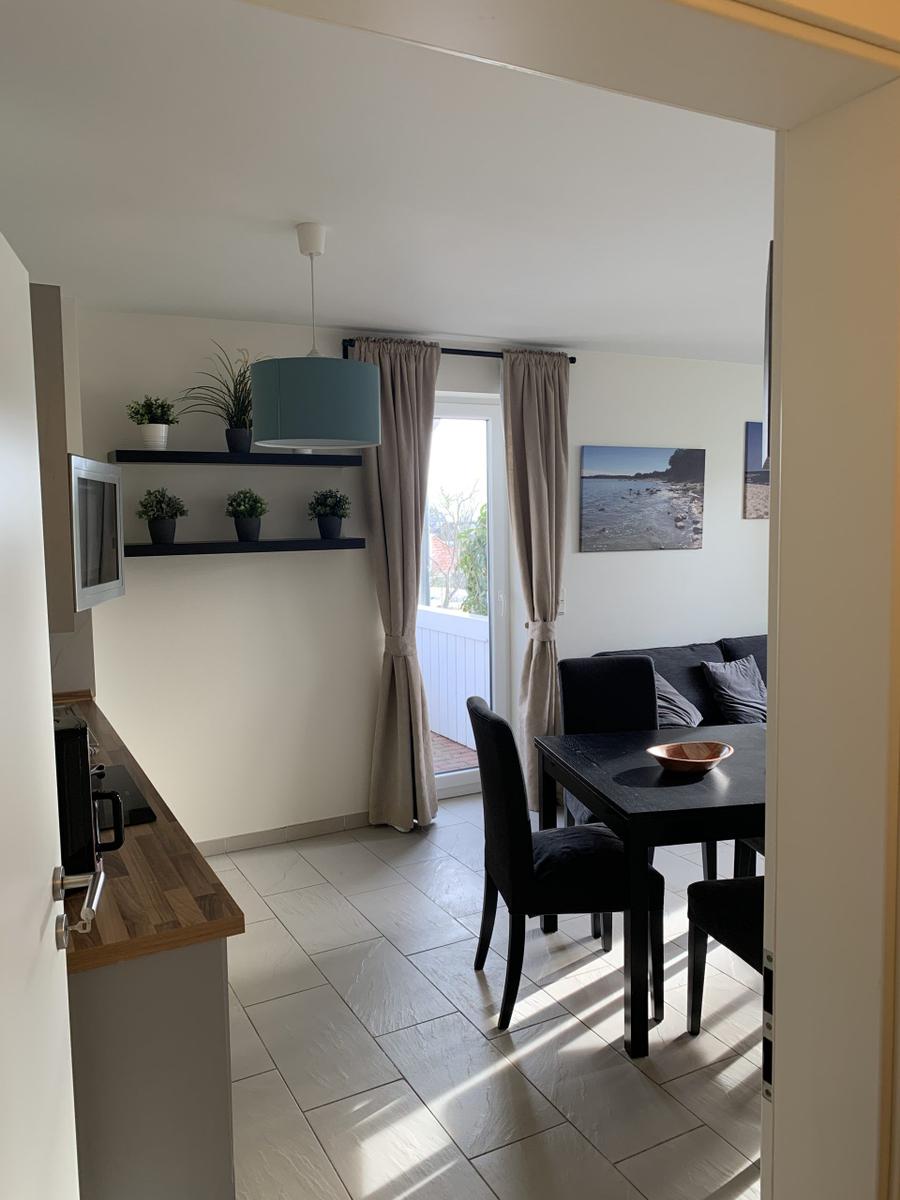 Küche mit Esstisch, Sofa und Fenster zum Balkon.