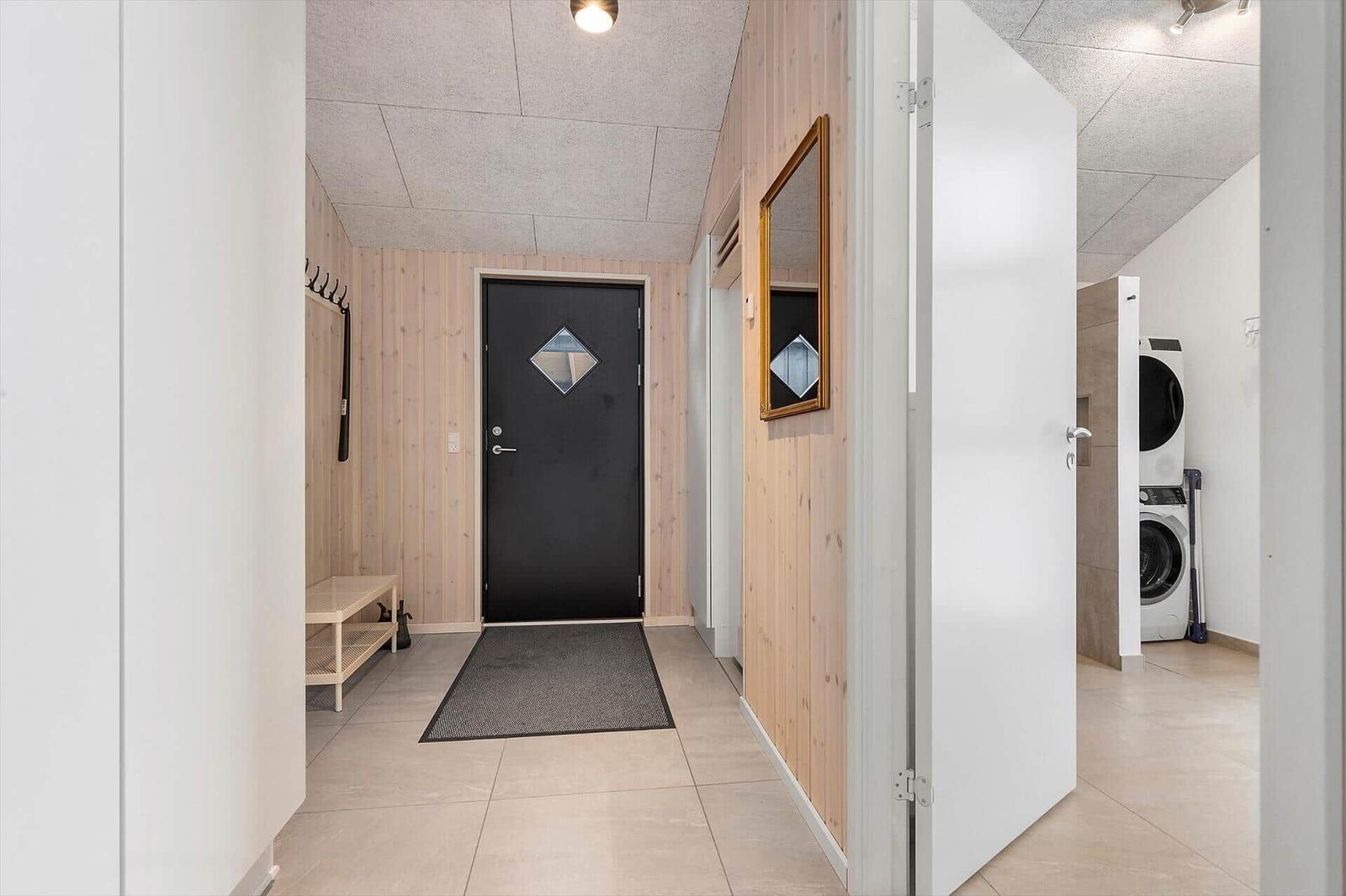 Eingangsbereich mit Holzwand, Spiegel und Waschmaschine im Anschluss