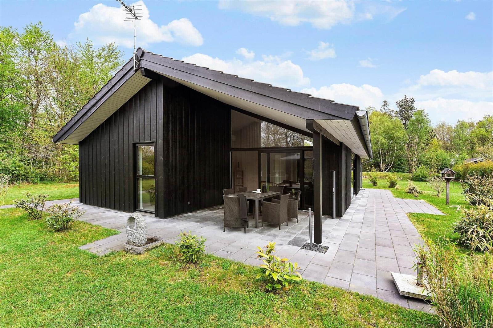 Moderne Holzhütte mit Terrasse und Garten. Essbereich im Freien.