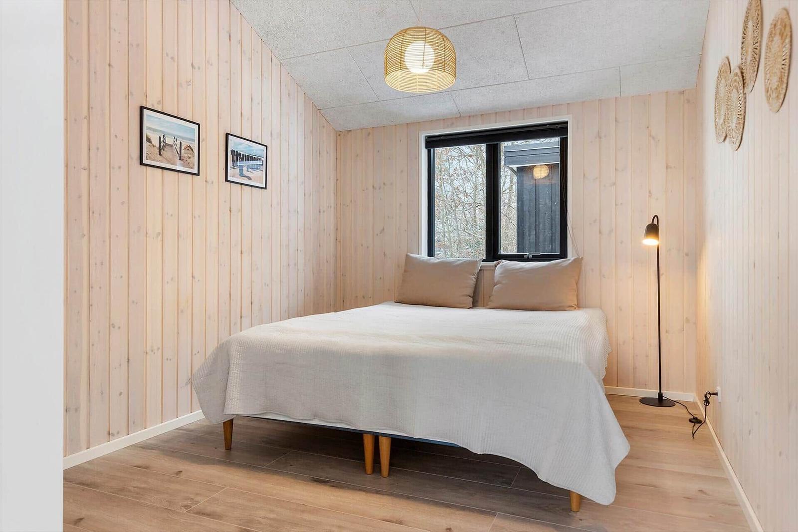 Schlafzimmer mit Bett, Fenster und Lampen an den Wänden.