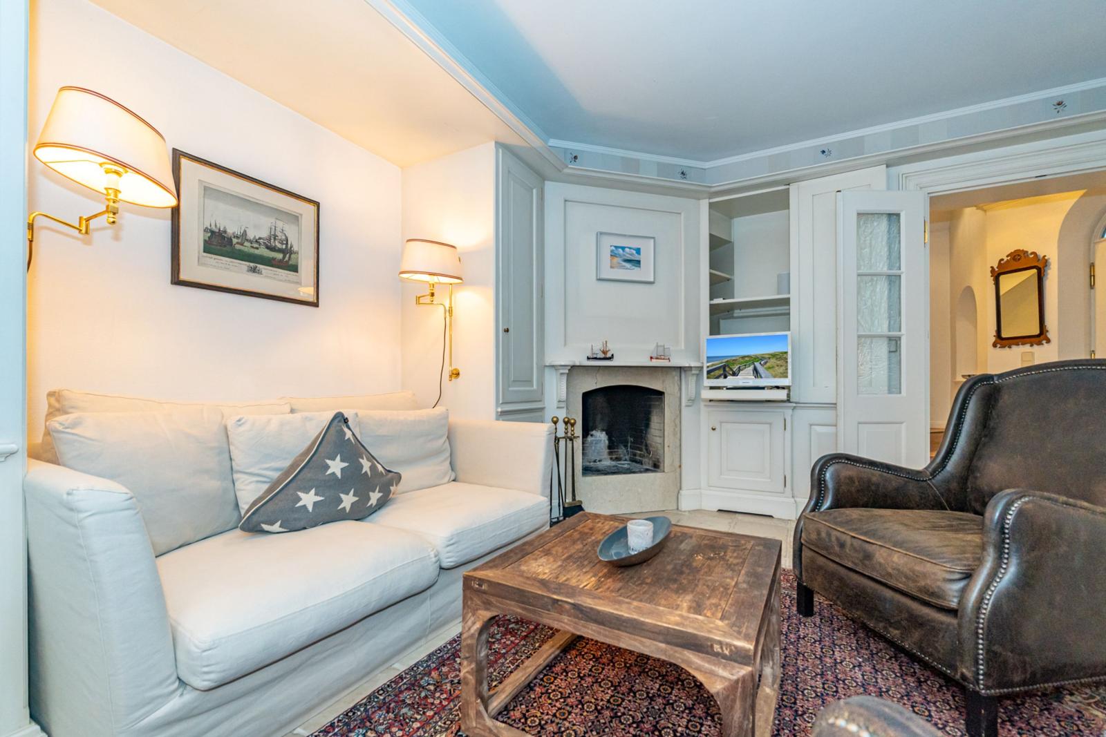 Wohnzimmer mit Sofa, Ledersessel, Kamin und Holztisch.