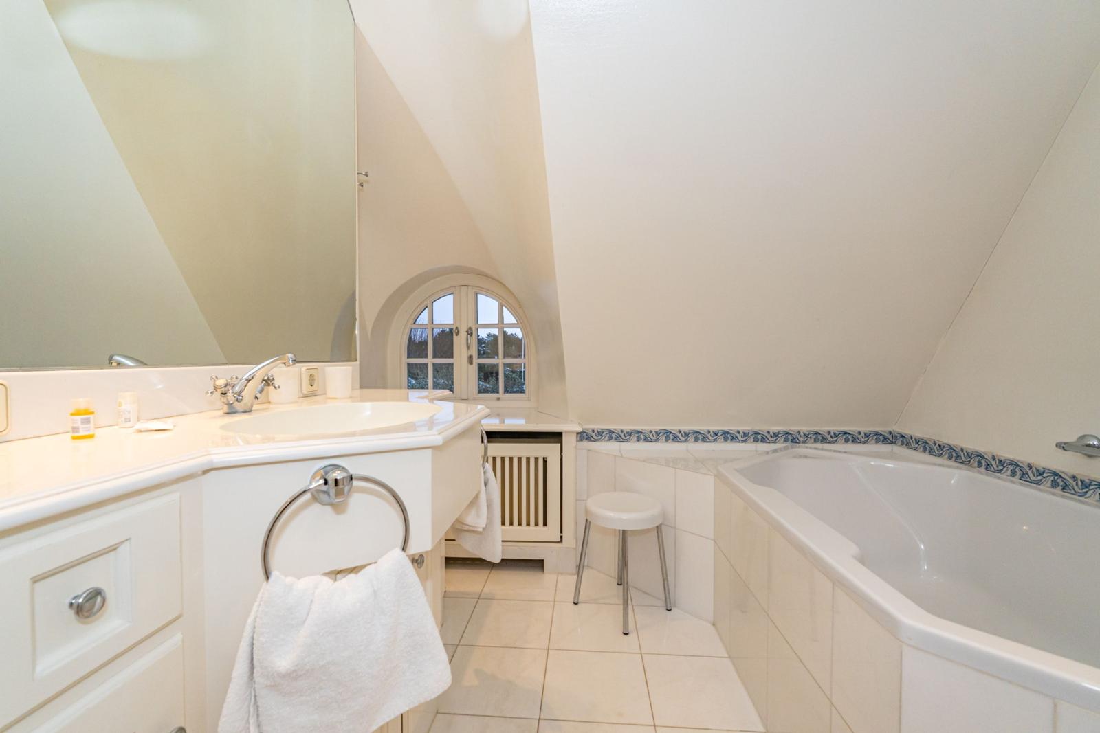 Badezimmer mit Badewanne, Waschbecken und kleinem Fenster.