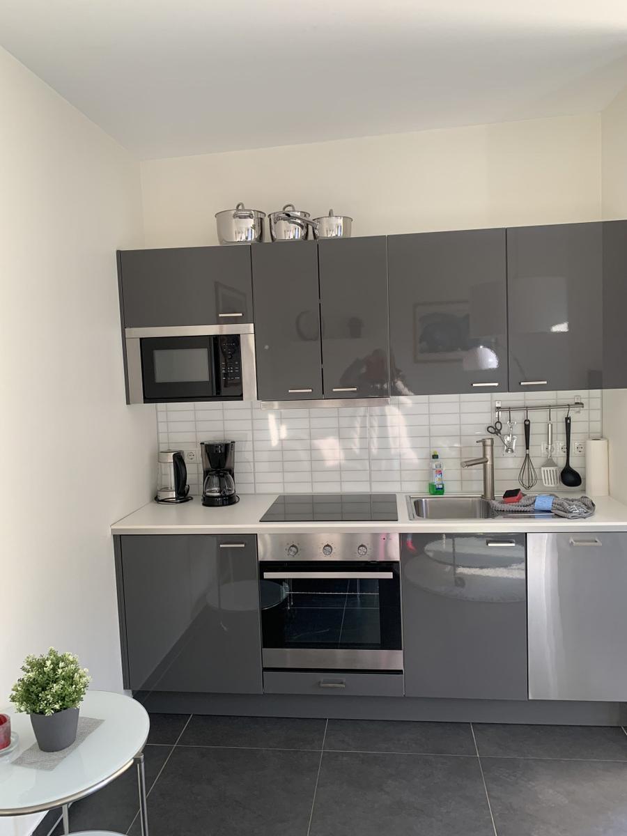 Moderne Küche mit grauen Schränken, Herd, Spüle und Mikrowelle.