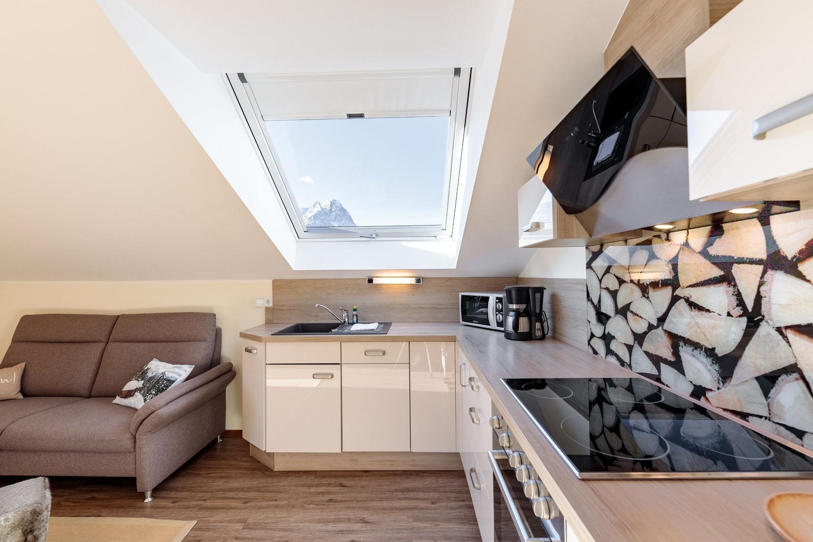 Küche mit Sofa und Dachfenster mit Bergblick.
