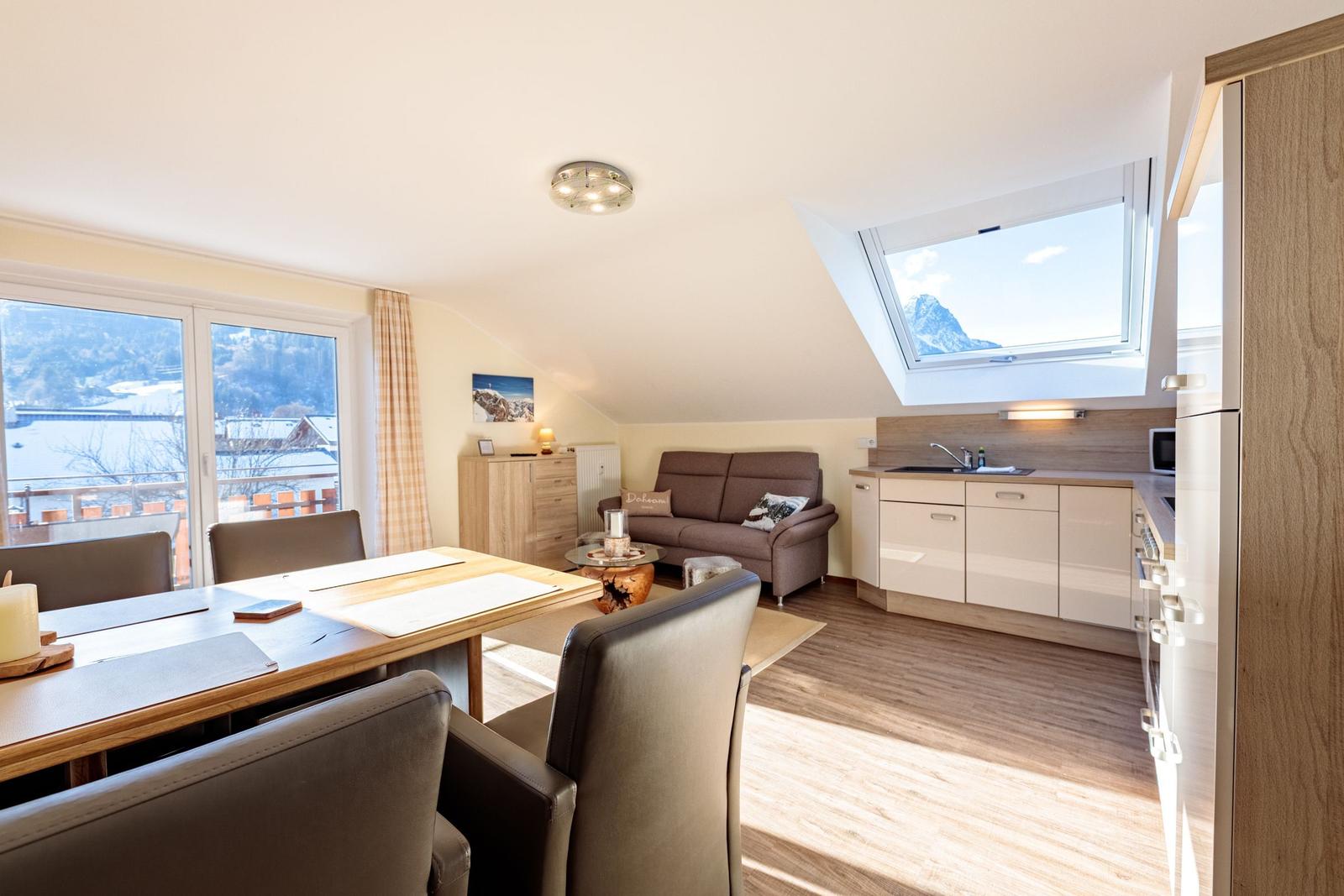 Wohnküche mit Essbereich, Sofa und Dachfenster mit Bergblick.
