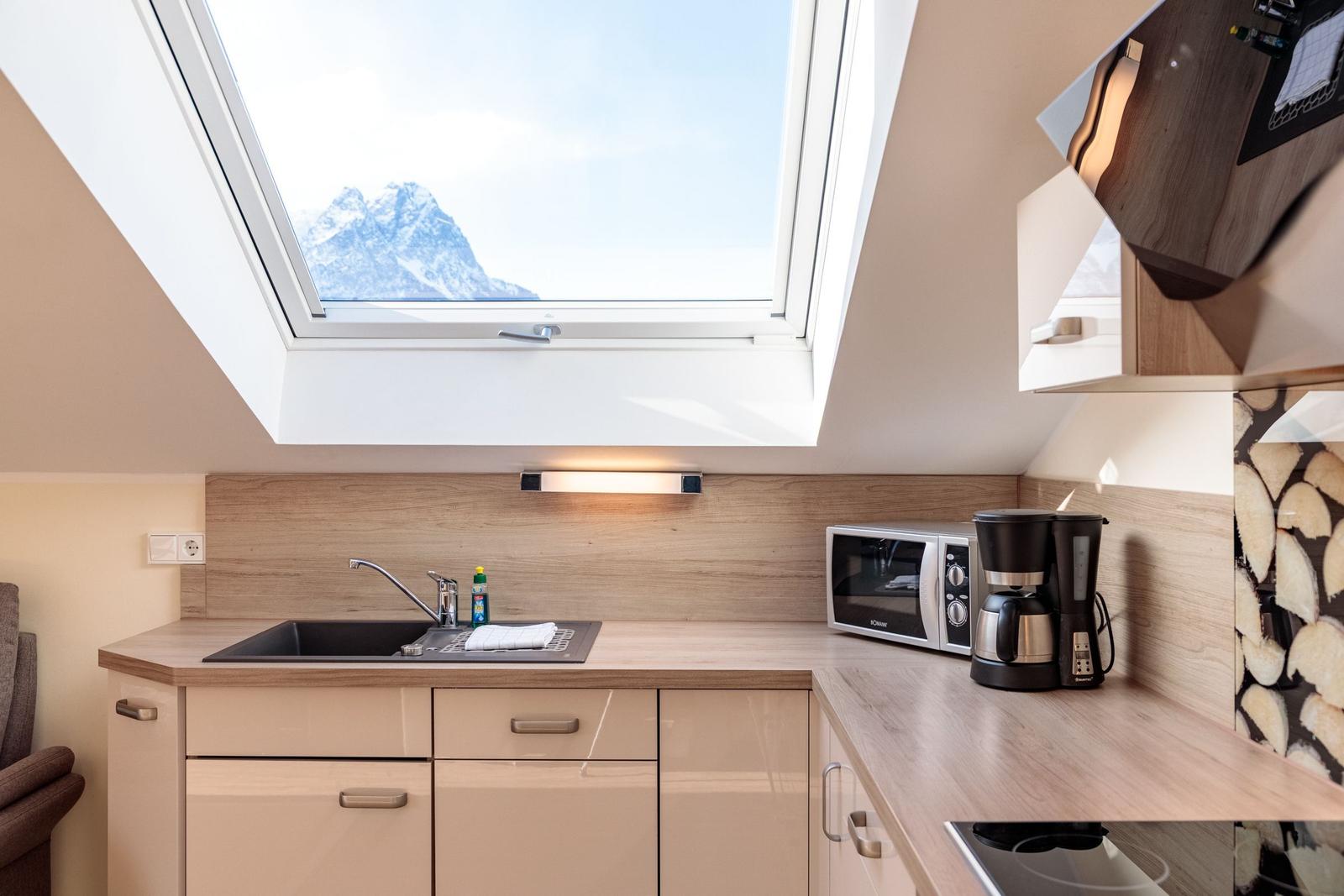 Küche mit Dachfenster, Mikrowelle und Kaffeemaschine. Blick auf schneebedeckte Berge.