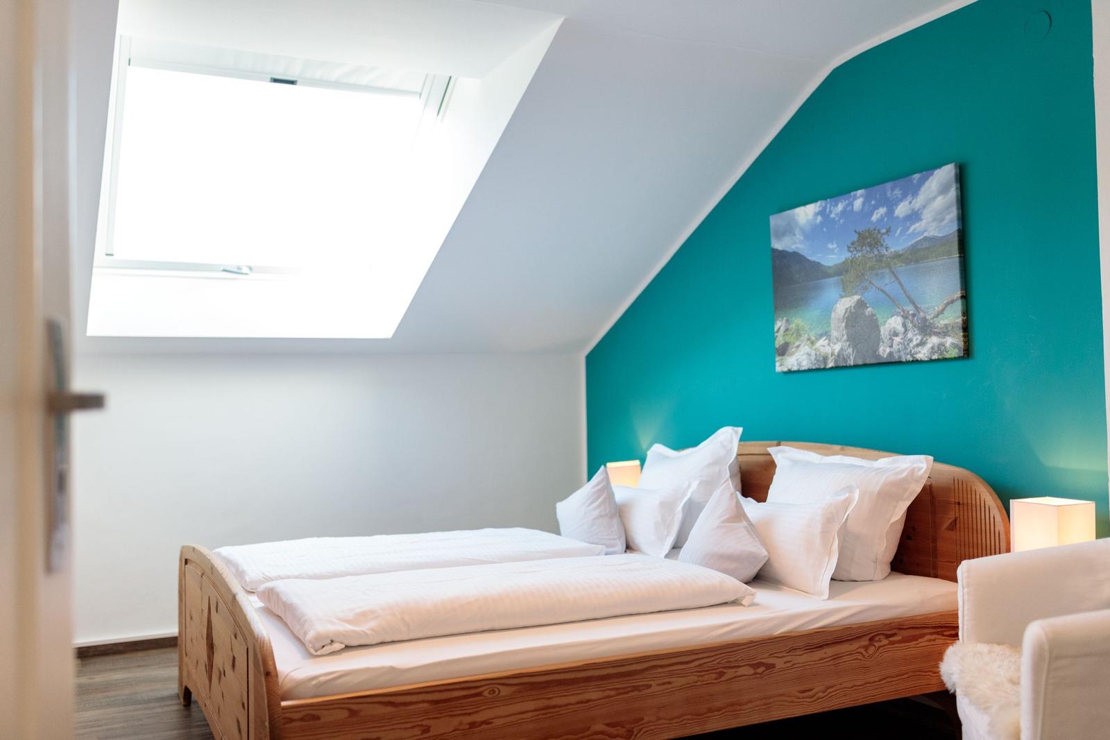 Schlafzimmer mit Dachschrägen, Dachfenster und Holzbett.