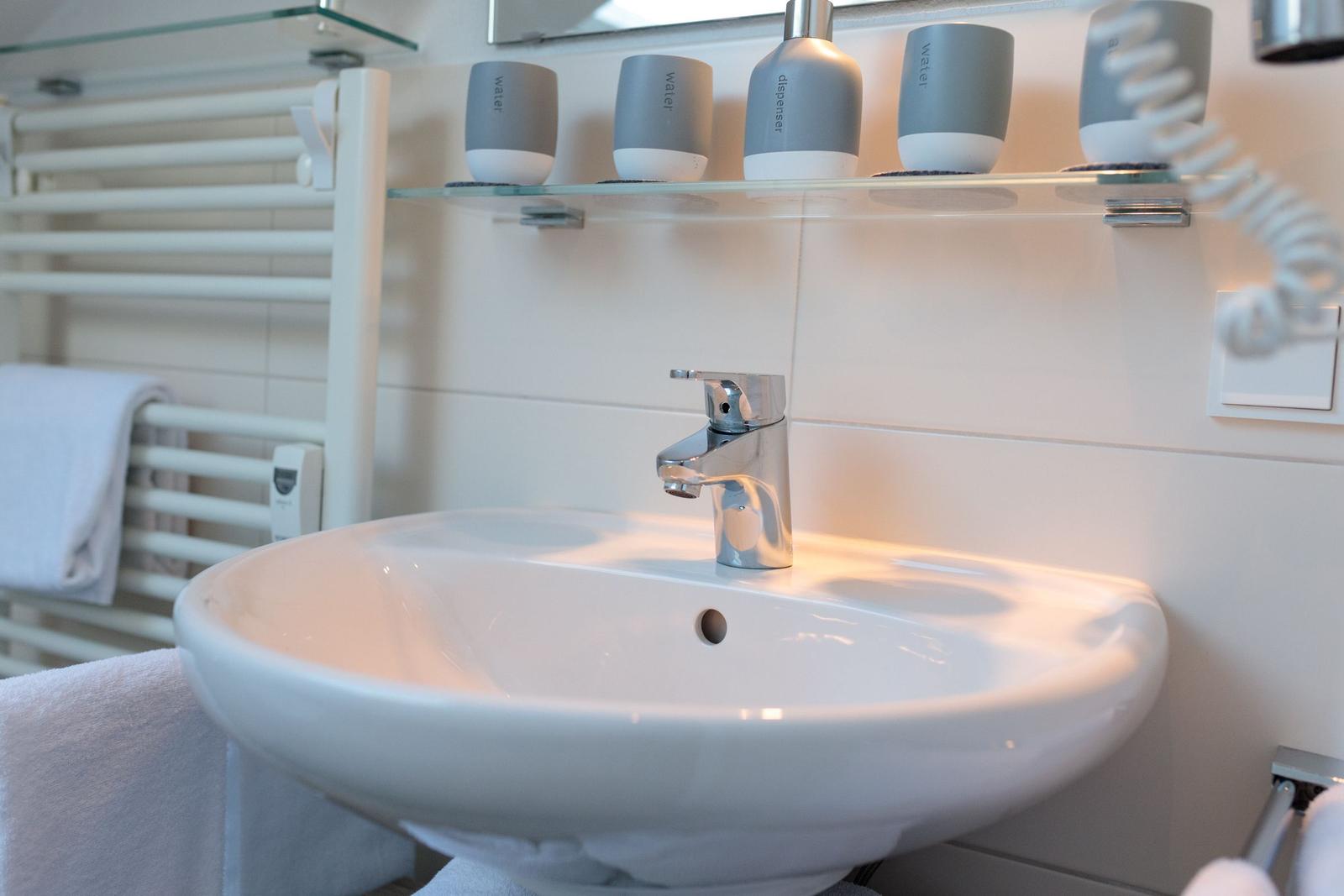 Waschbecken mit Wasserflaschen und Handtuchhalter im Badezimmer.