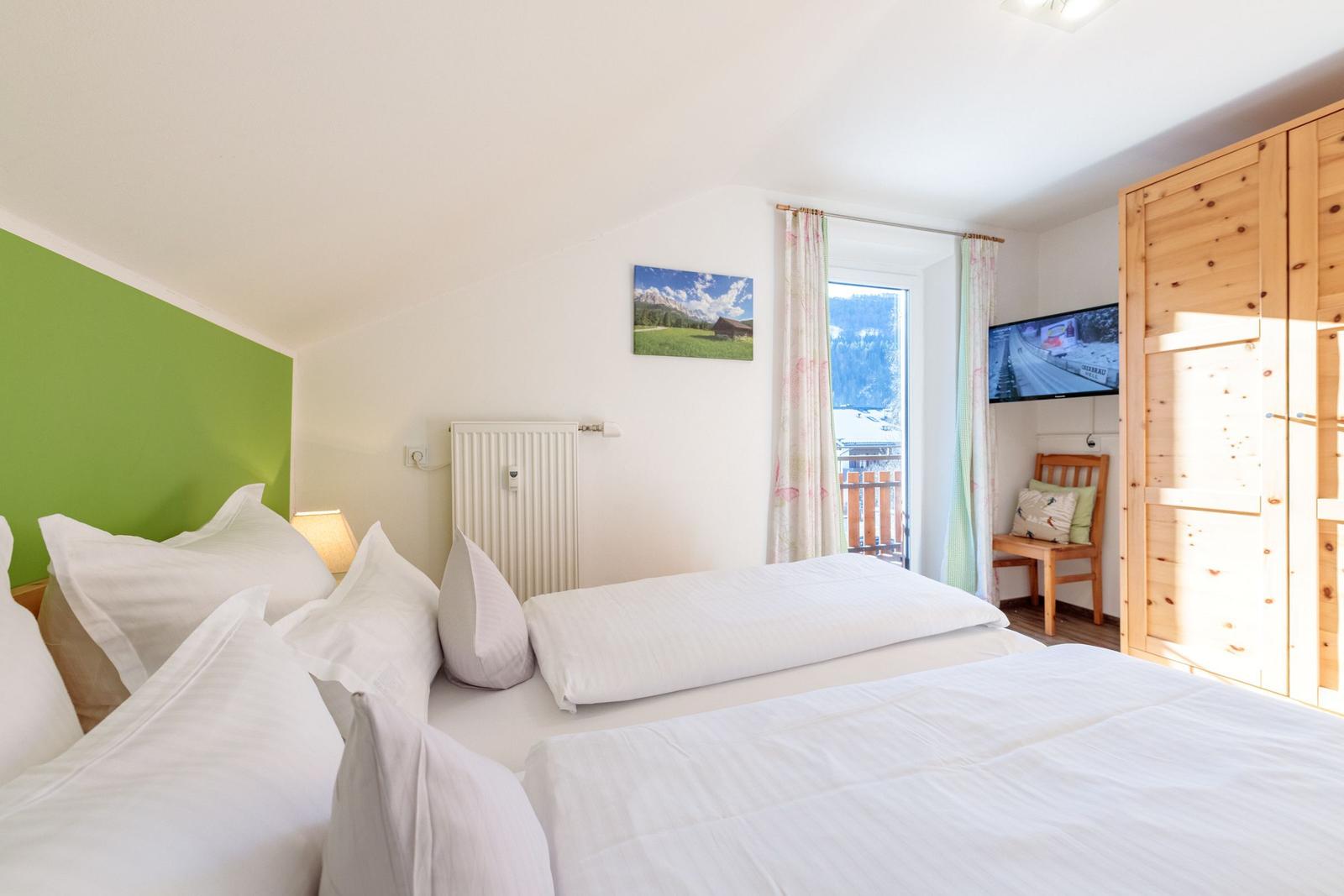Schlafzimmer mit Doppelbett, Fenster und Holzschrank.