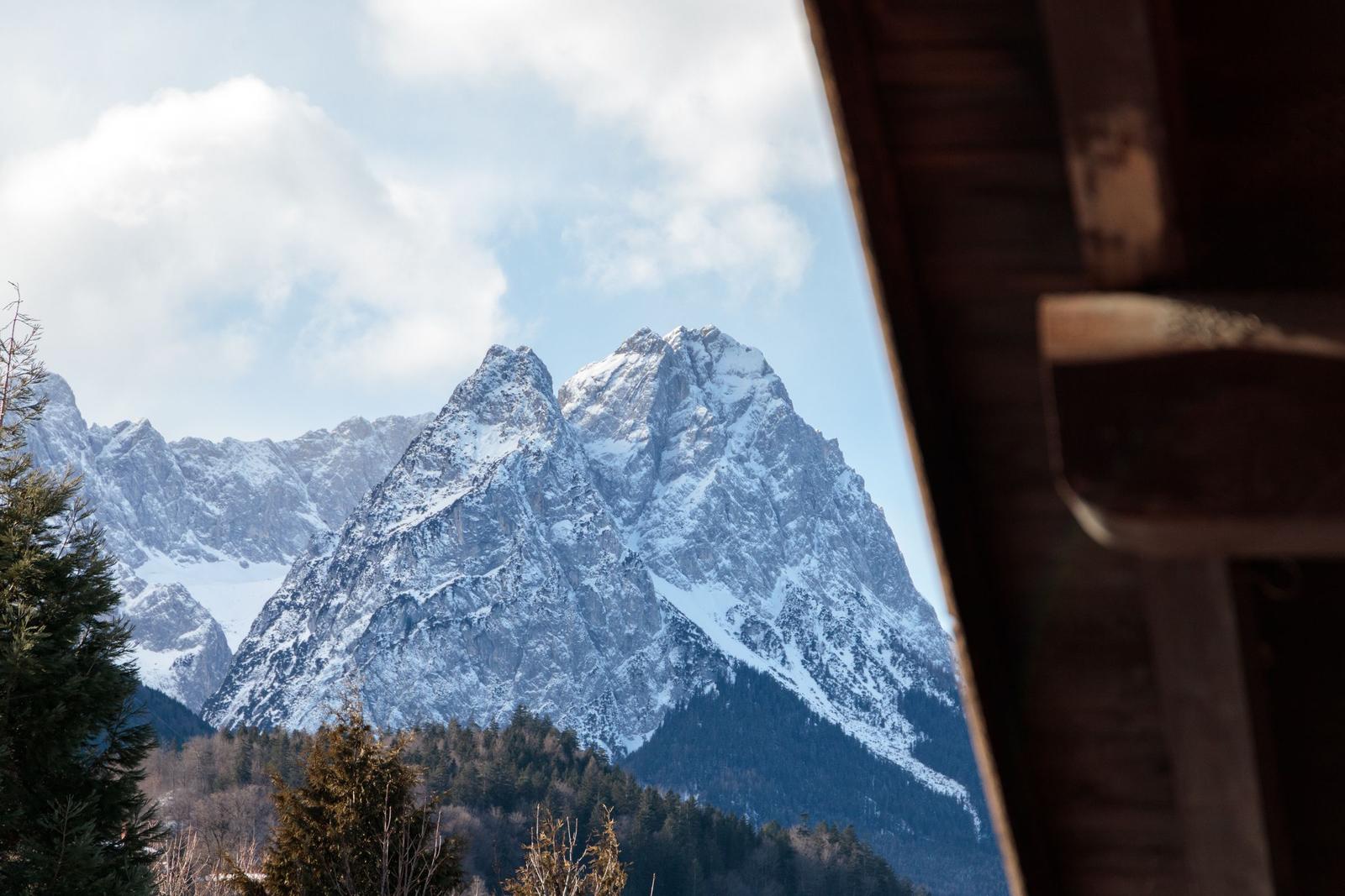 Schneebedeckte Berge sind durch ein Holzfenster sichtbar.