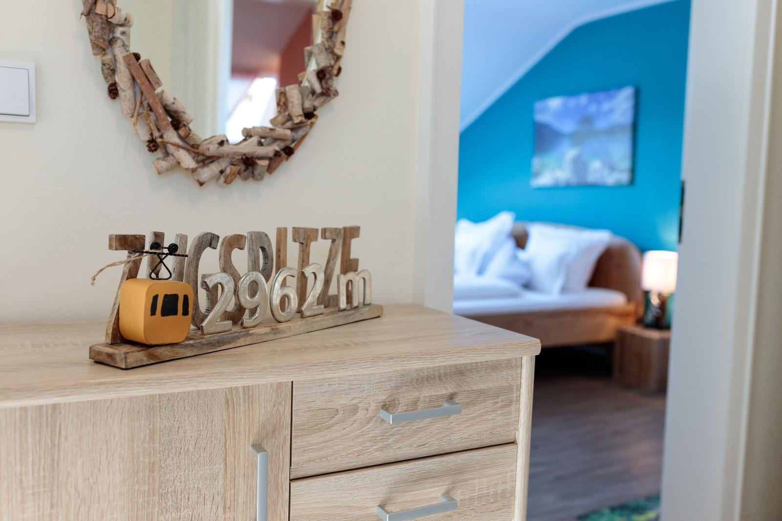 Schrank mit Dekoration und Blick in Schlafzimmer mit blauer Wand