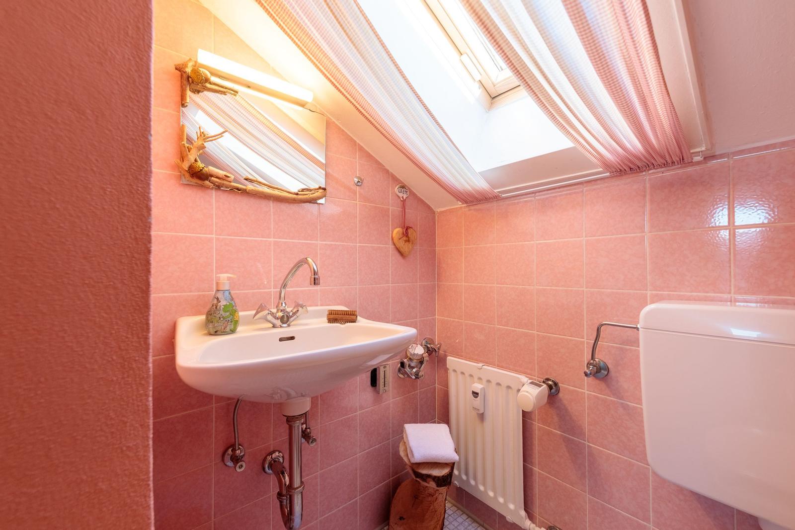 Badezimmer mit Waschbecken, Spiegel und Dusche unter Dach