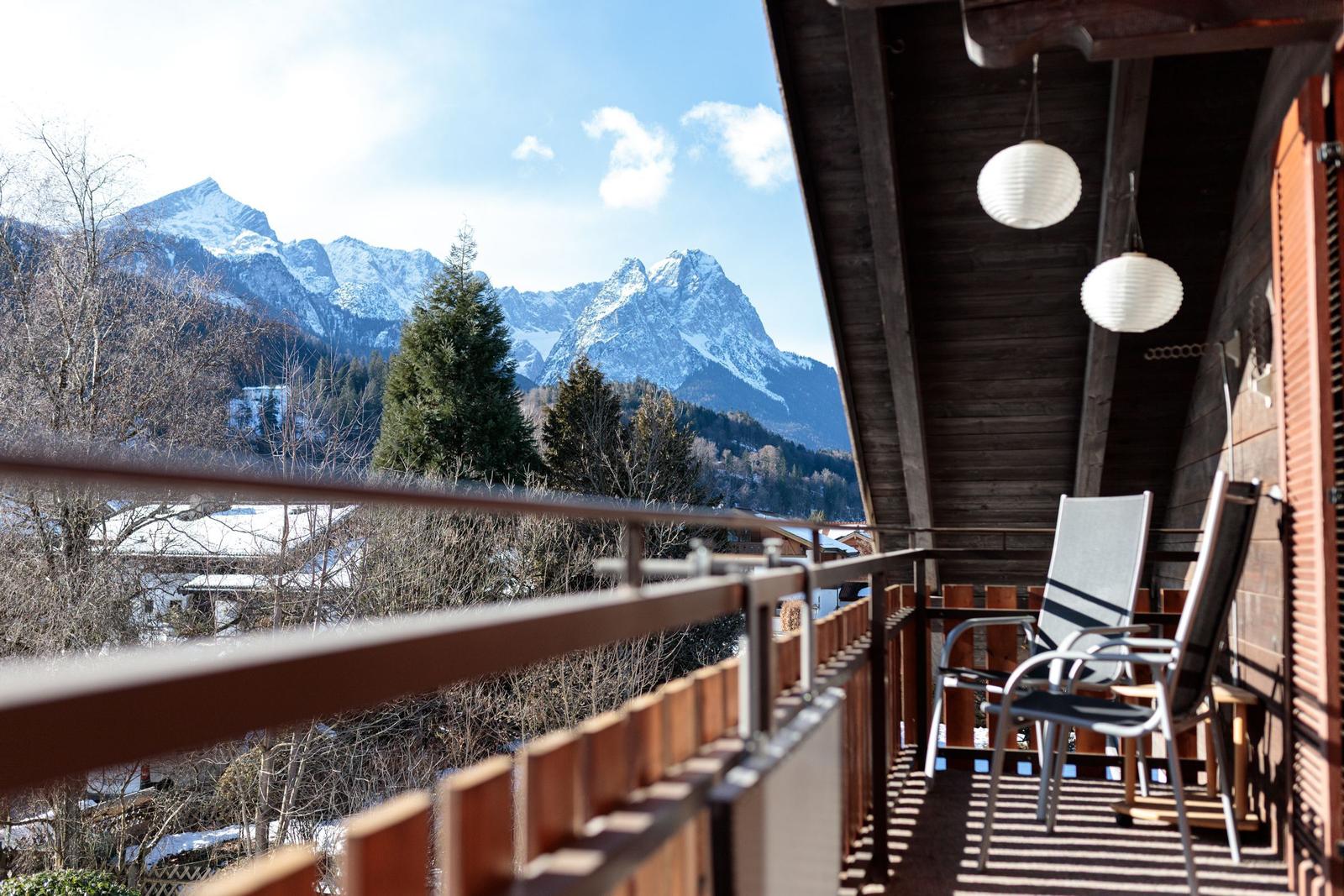 Terrasse mit Blick auf schneebedeckte Berge und Bäume.
