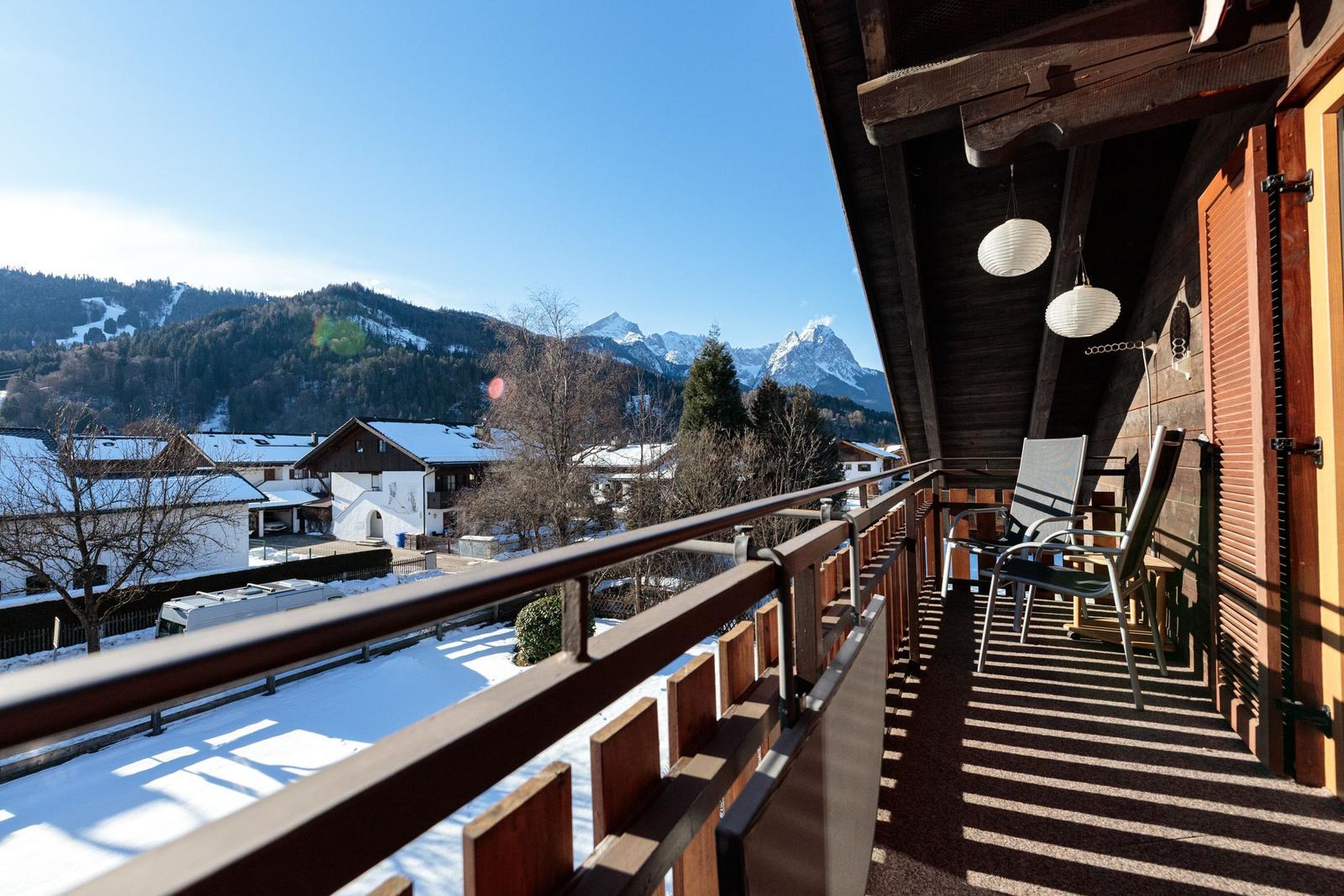 Terrasse mit Sicht auf schneebedeckte Berge und Dorf.