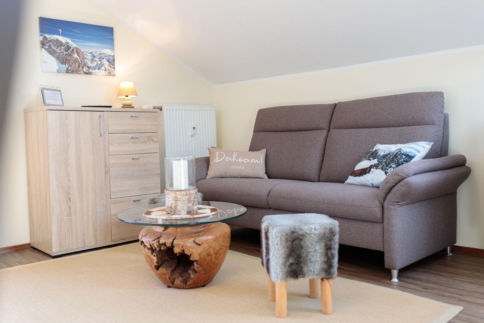 Wohnzimmer mit Sofa, Couchtisch und Schrank unter Dachschrägen.