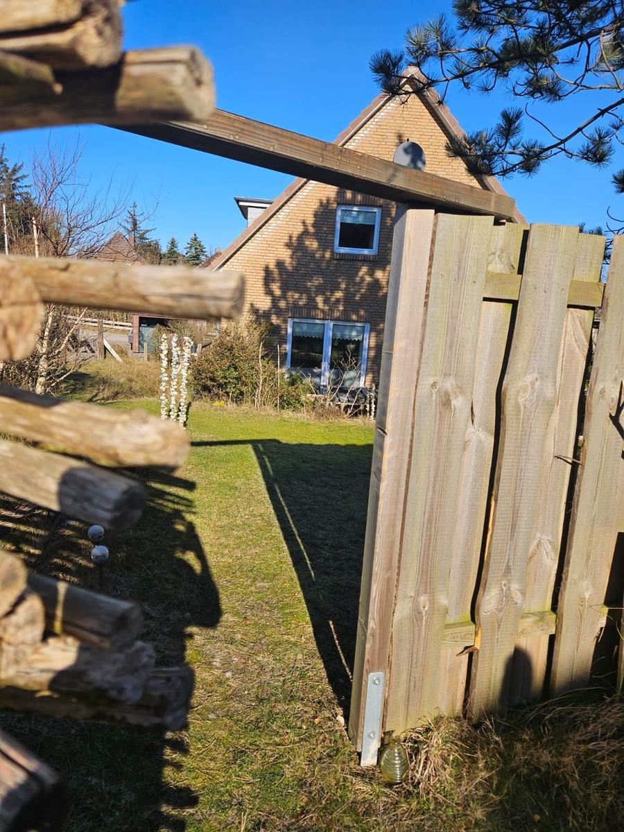 Hinterhof mit Holzzaun und Blick auf Haus mit Fenstern.