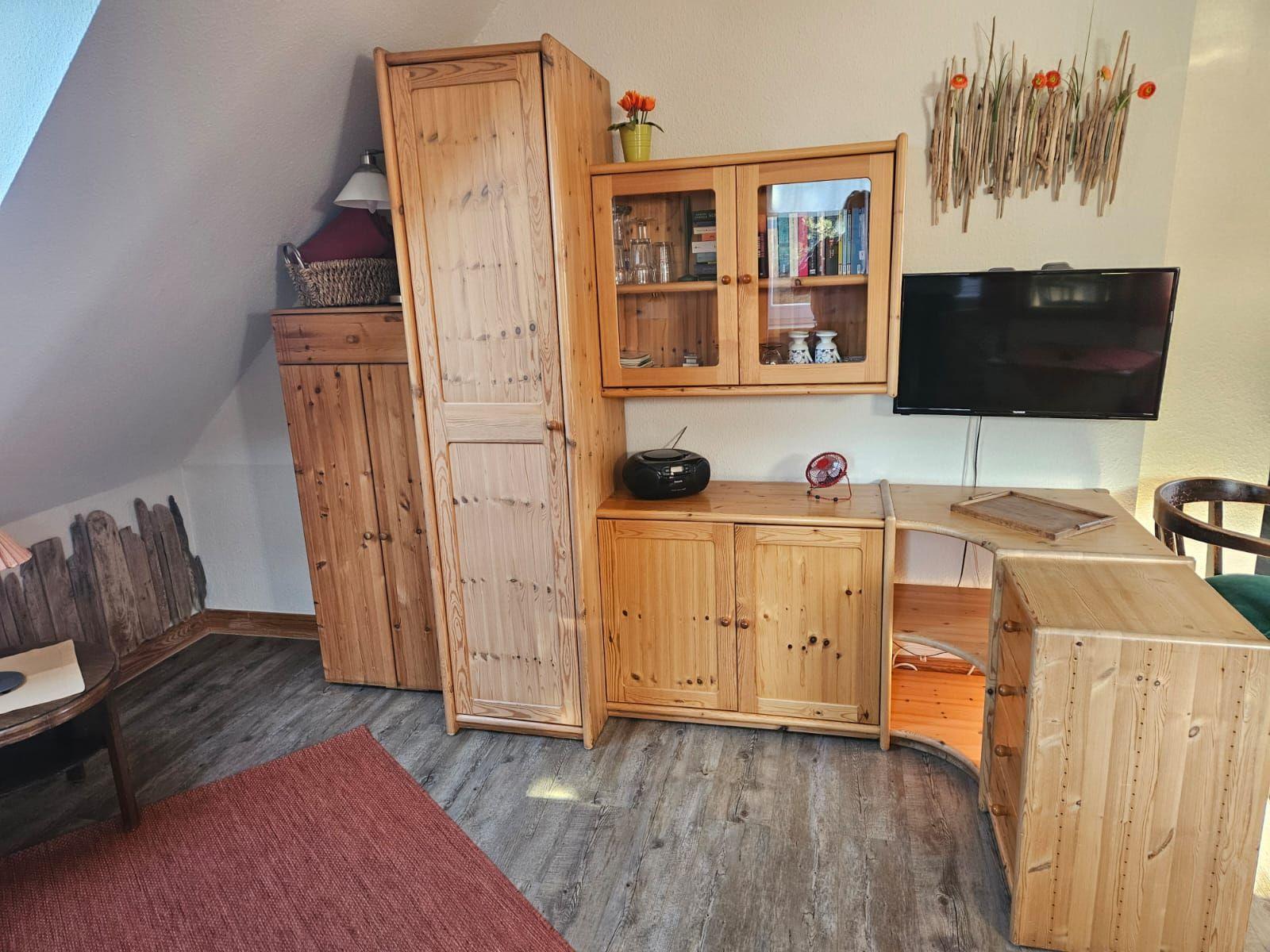 Zimmer mit Holzmöbeln, Fernseher und rotem Teppich