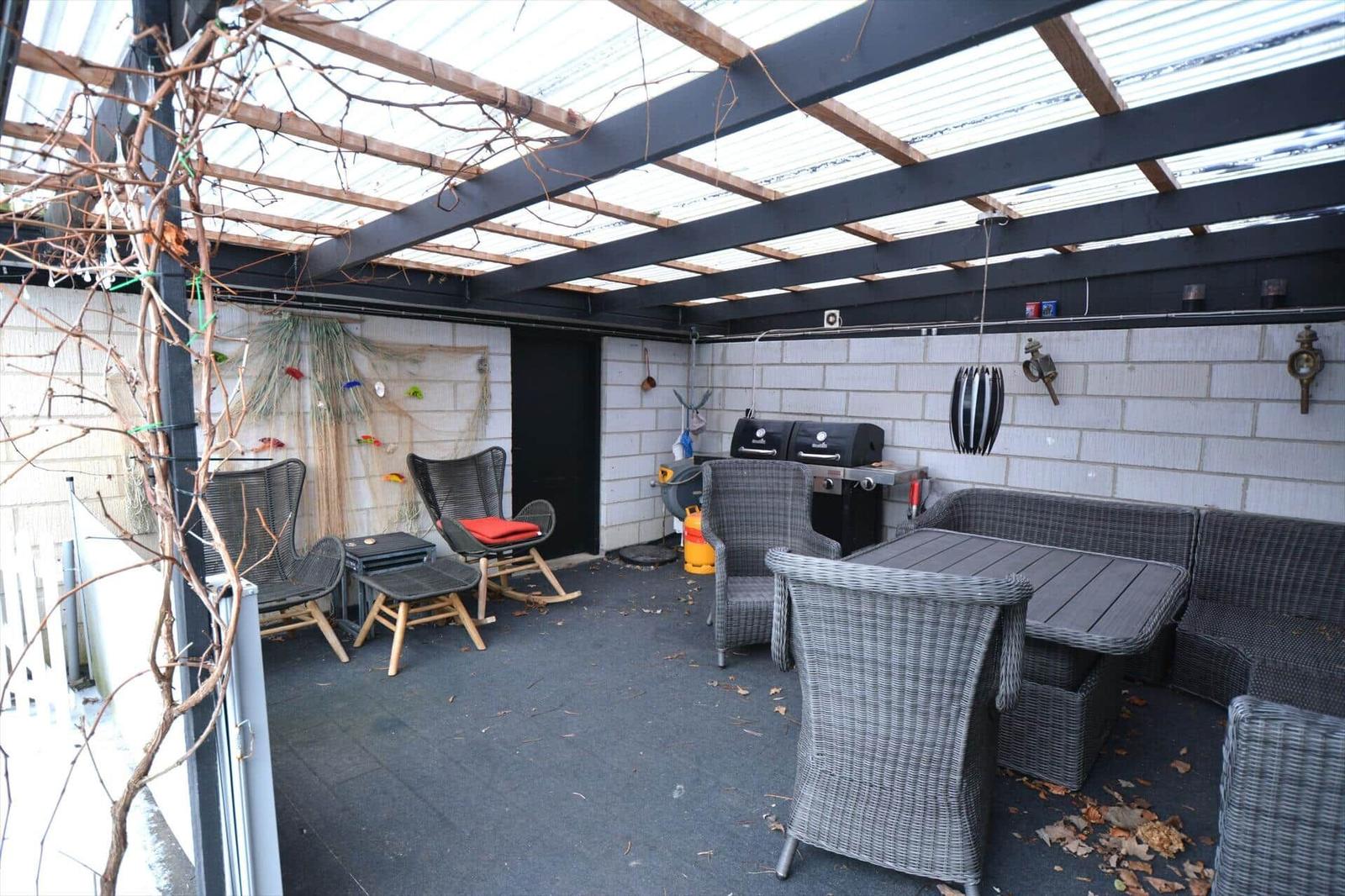 Terrasse mit Sitzgruppe, Grill und Pergola unter transparentem Dach.