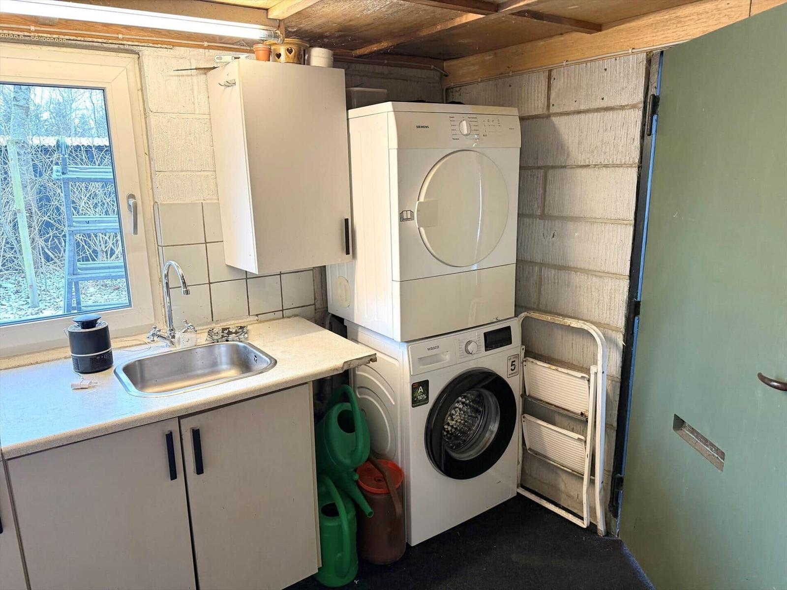 Wäscherei mit Waschmaschine und Trockner, Spüle und Fenster.