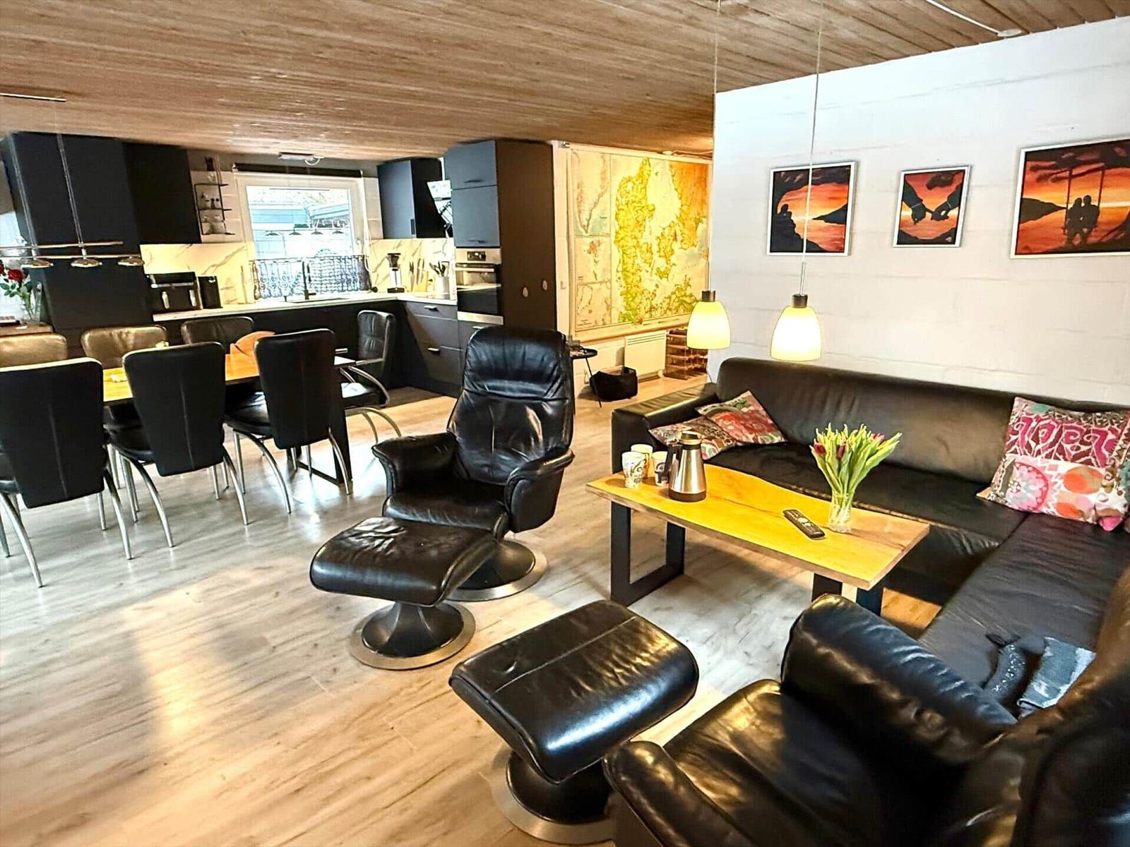 Wohn- und Essbereich mit Küchenzeile, Sofa und Ledersessel.