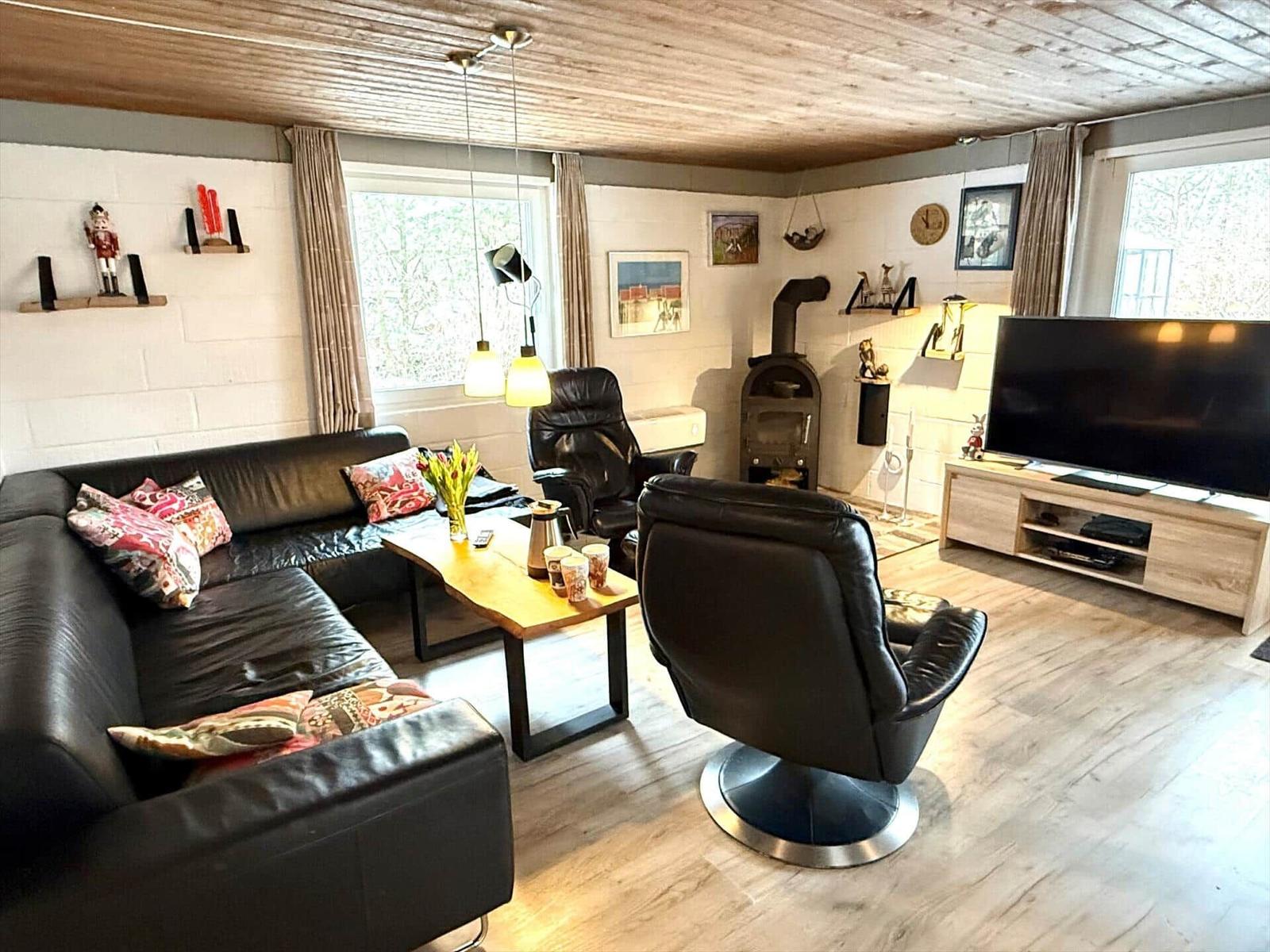 Wohnzimmer mit Sofa, Sessel, Kamin und TV.