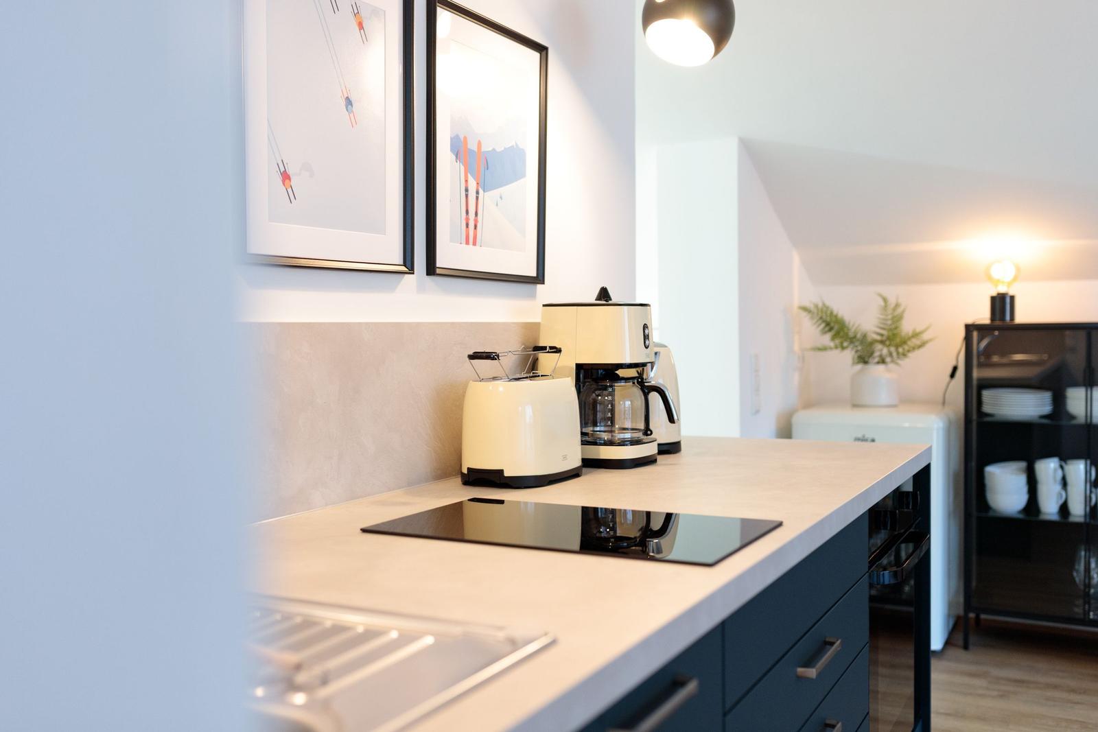 Küche mit Kaffeemaschine, Toaster und Induktionskochfeld.