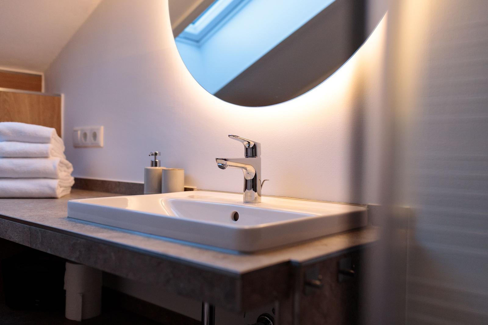 Waschbecken mit Spiegel und Handtuchstapel