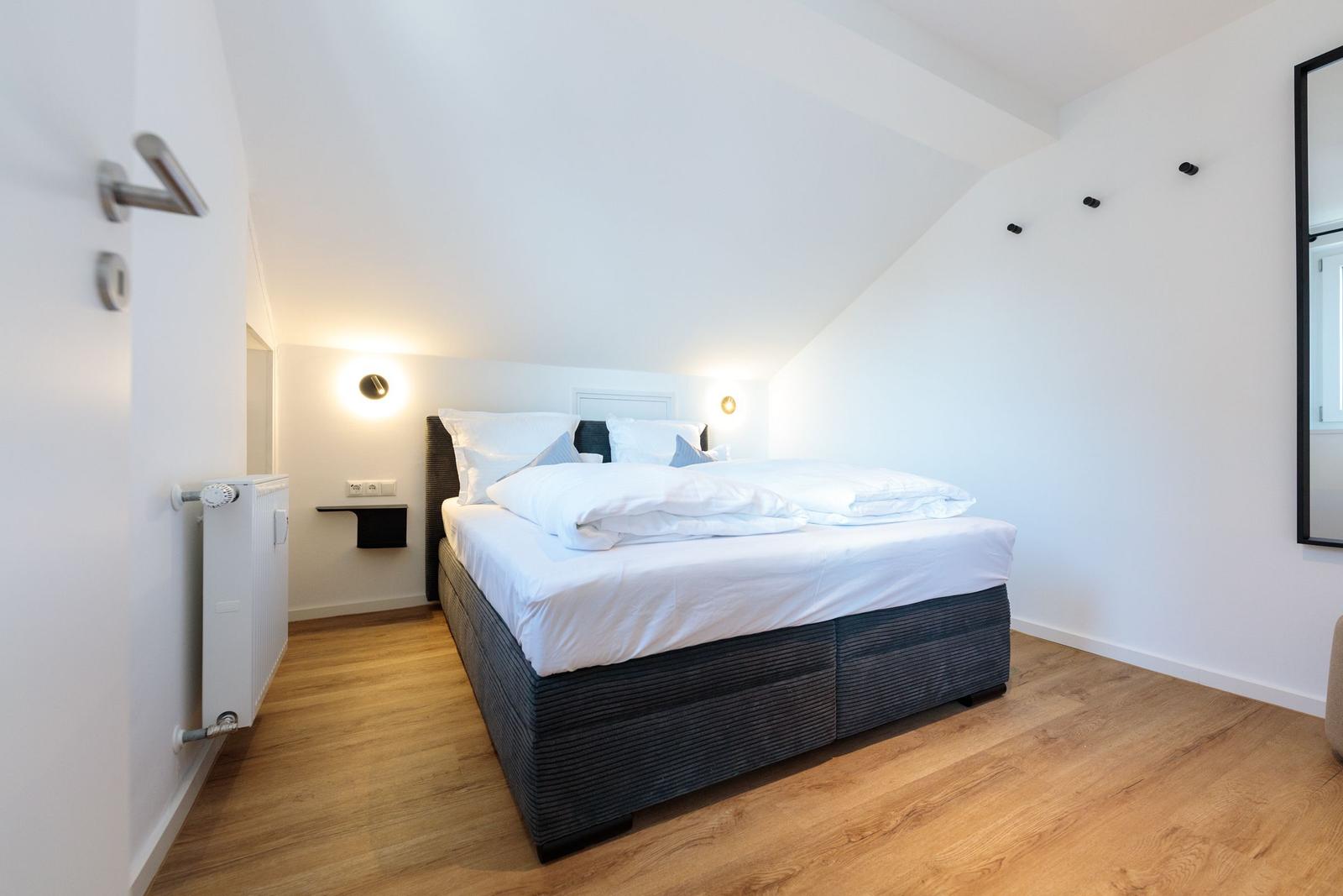 Schlafzimmer mit Doppelbett, Holzboden und schrägen Wänden.