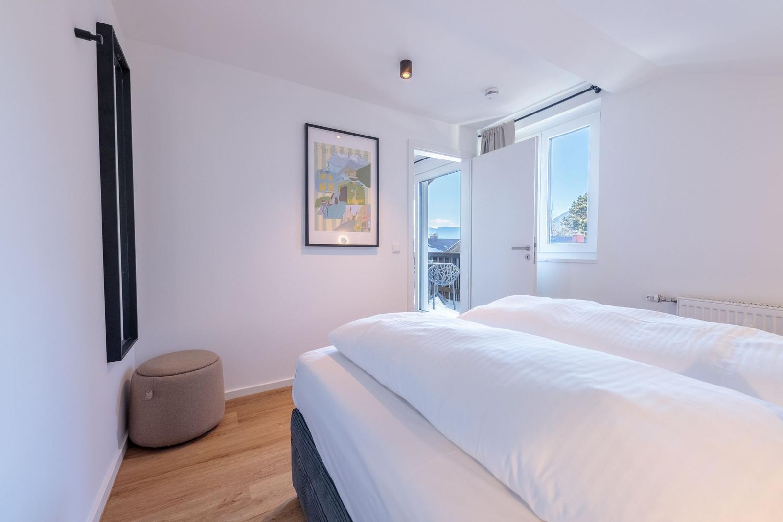 Schlafzimmer mit Doppelbett, Fenster und Balkontür.