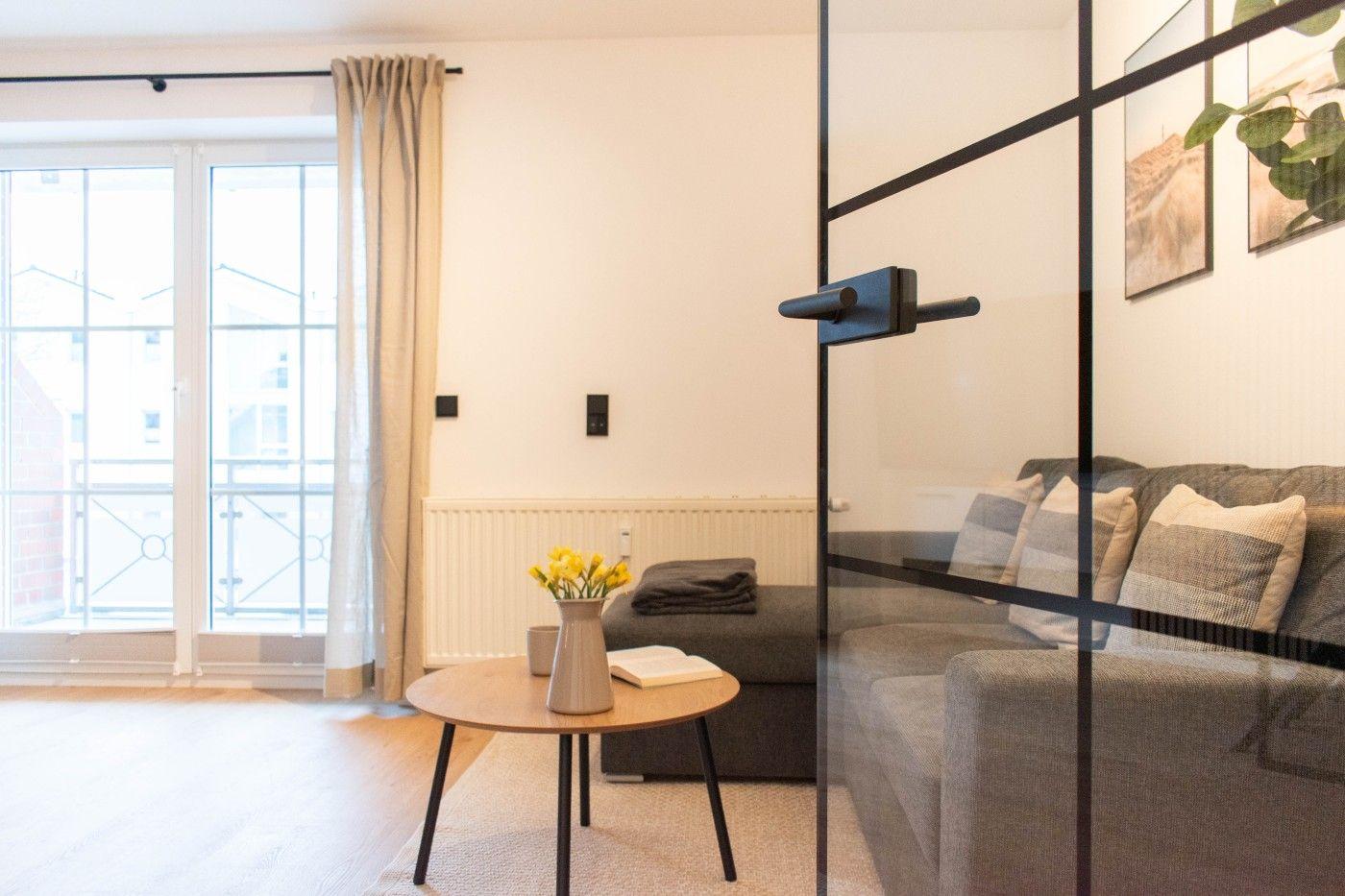 Wohnbereich mit Sofa, Tisch und Blick auf Balkon