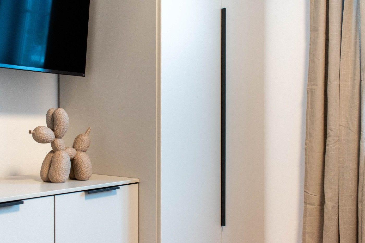 TV auf Wandmontage, Dekofigur auf Schrank, Vorhang rechts