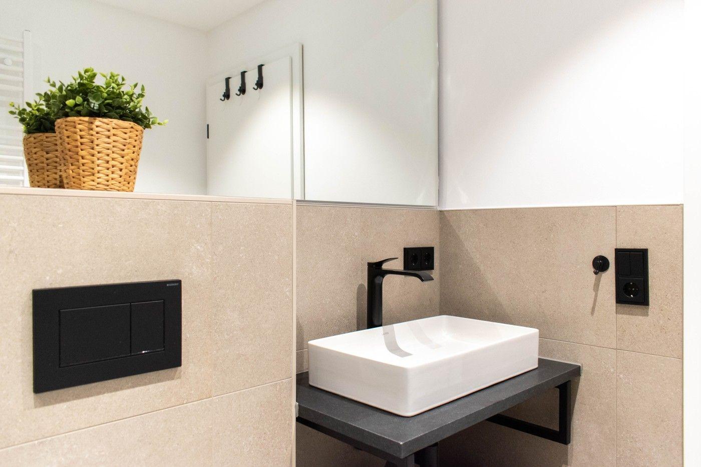 Badezimmer mit Waschbecken, Spiegel und Pflanze