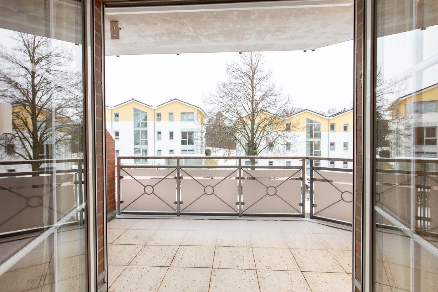 Terrasse mit Glasbrüstung und Blick auf Wohnhäuser
