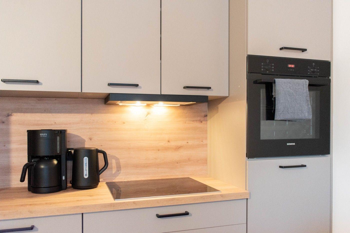 Küche mit Dunstabzug, Kaffeebereiter und integriertem Ofen.