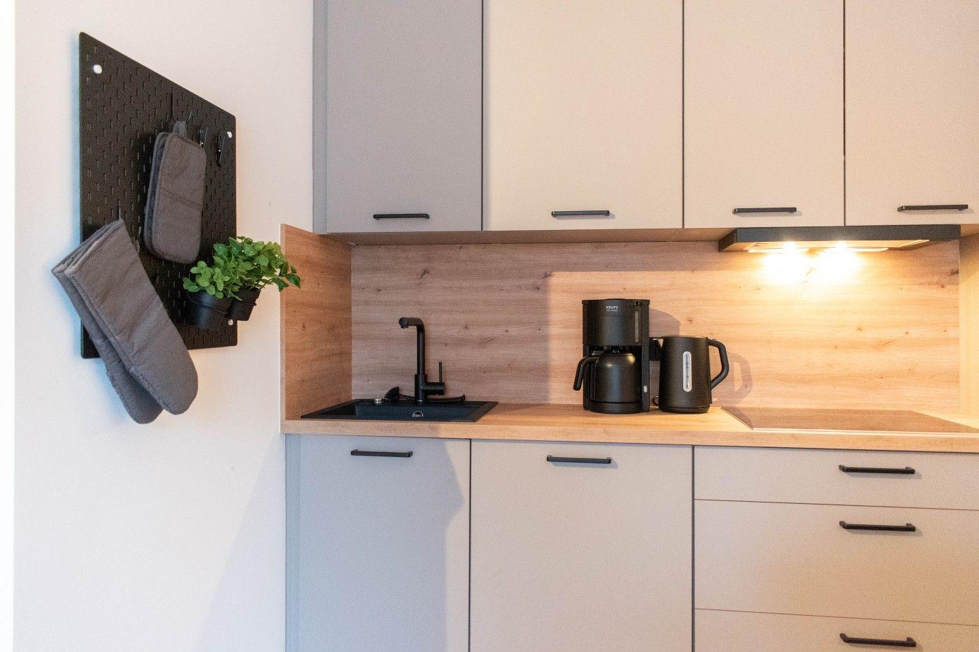 Küche mit Holzrückwand, Spüle, Kaffeemaschine und Küchengeräten.