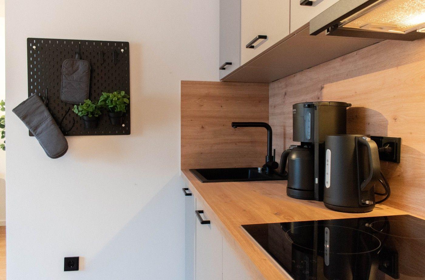 Küche mit Holz Arbeitsplatte, Spüle, Kaffeemaschine und Wasserkocher.