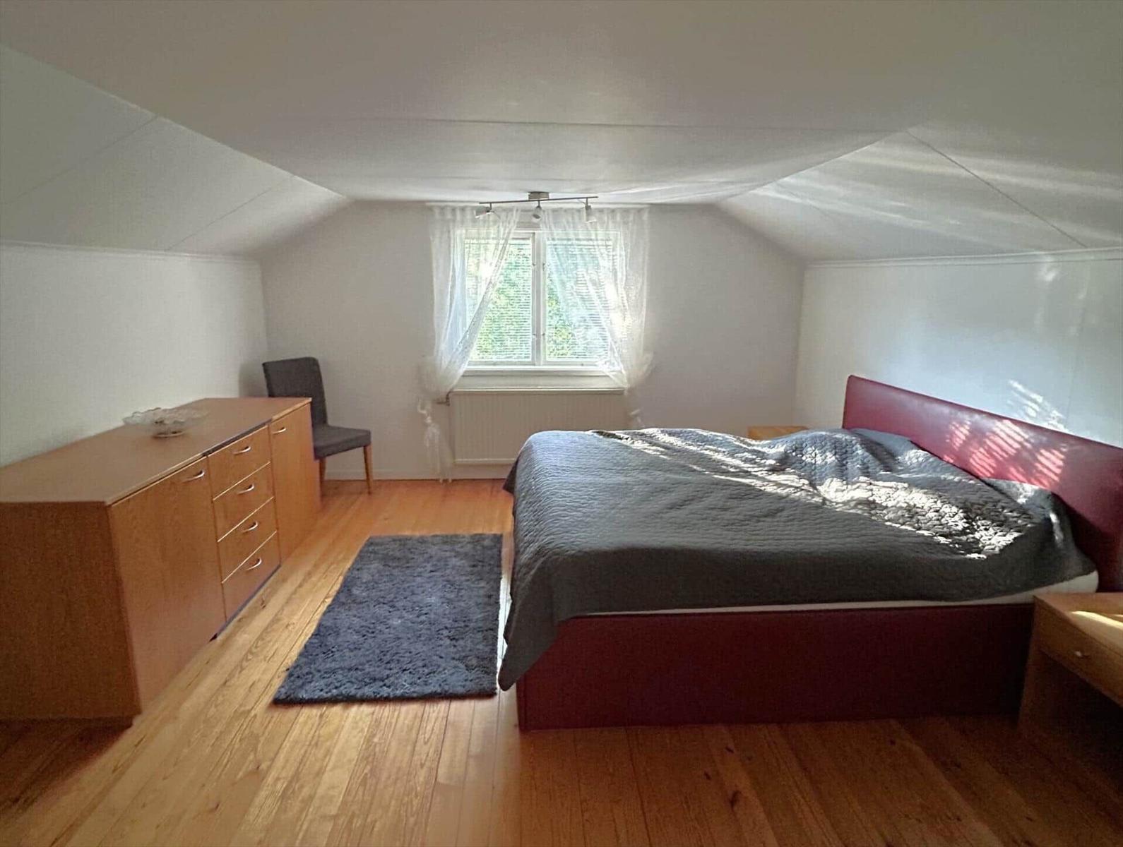 Schlafzimmer mit Dachschrägen, Bett, Schrank und Fenster.