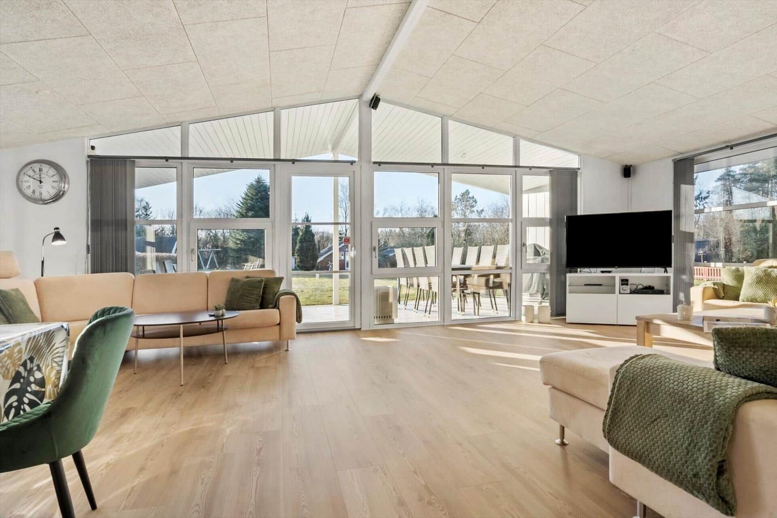 Living room with large windows, sofa, TV, and wooden floor.