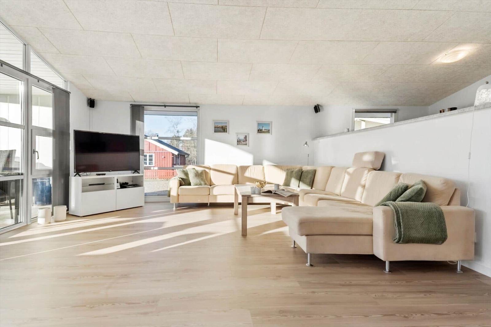 Living room with sofa, TV, and wooden floor. Access to terrace.