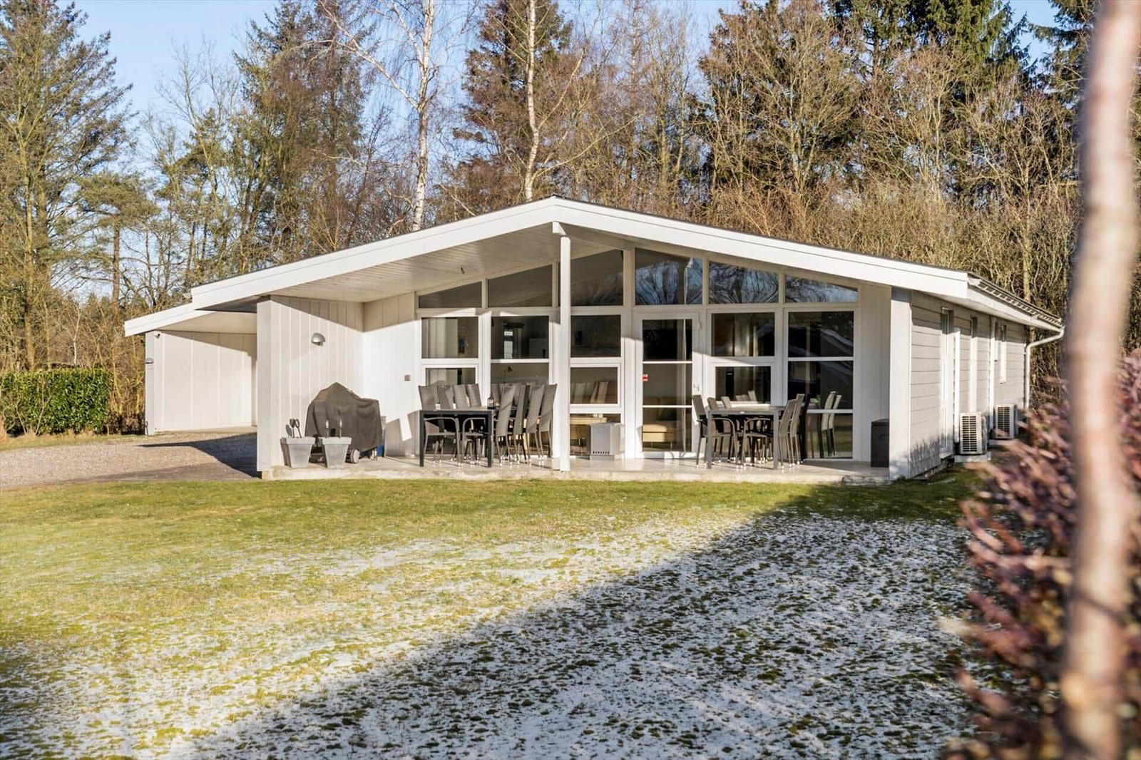 Modern villa with terrace, grill, and view of forest.