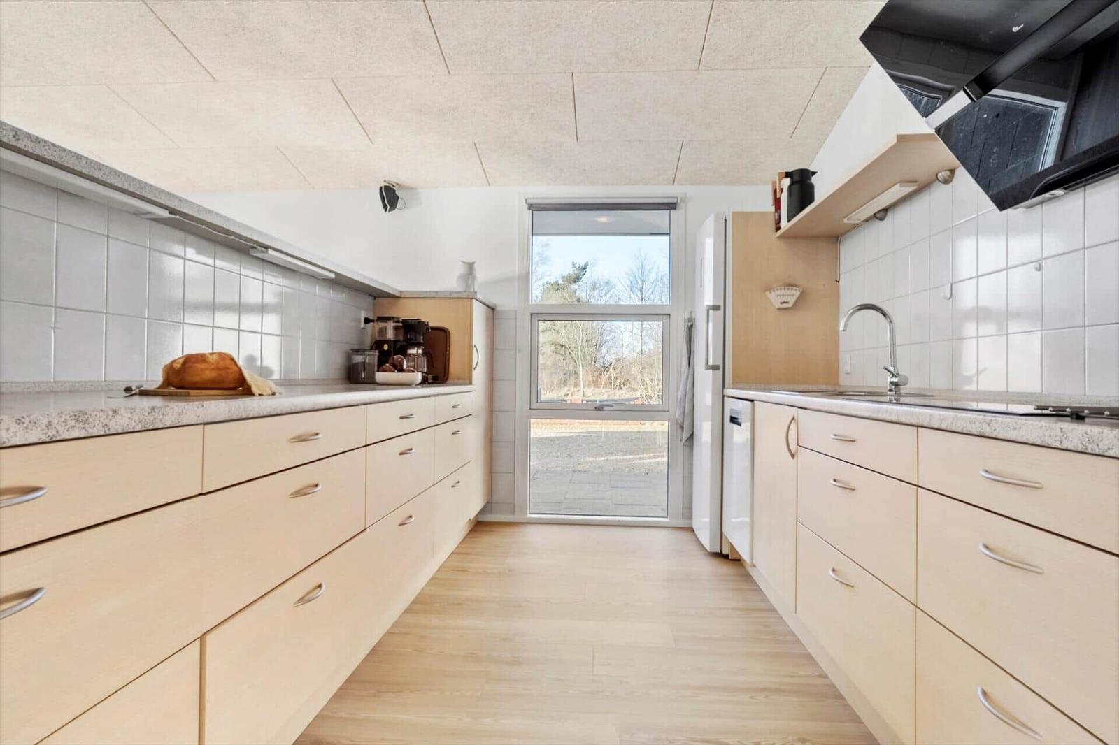 Modern kitchen with light cabinets, granite countertops, and window to outdoor area.