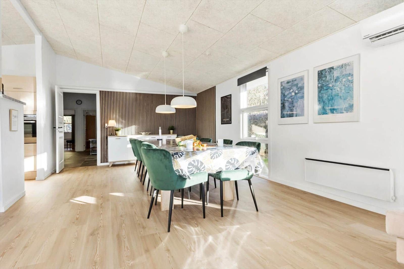 Dining room with green chairs and tablecloth. Kitchen area and window visible.