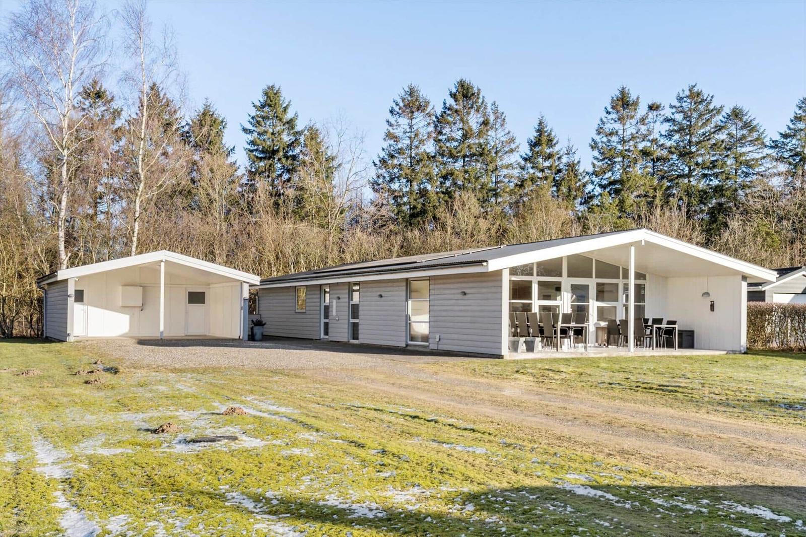 Modern holiday home with terrace and lawn. Surrounded by trees and grass area.