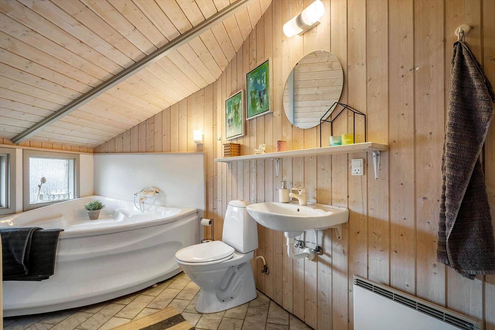 Bathroom with bathtub, toilet, and sink against wooden wall