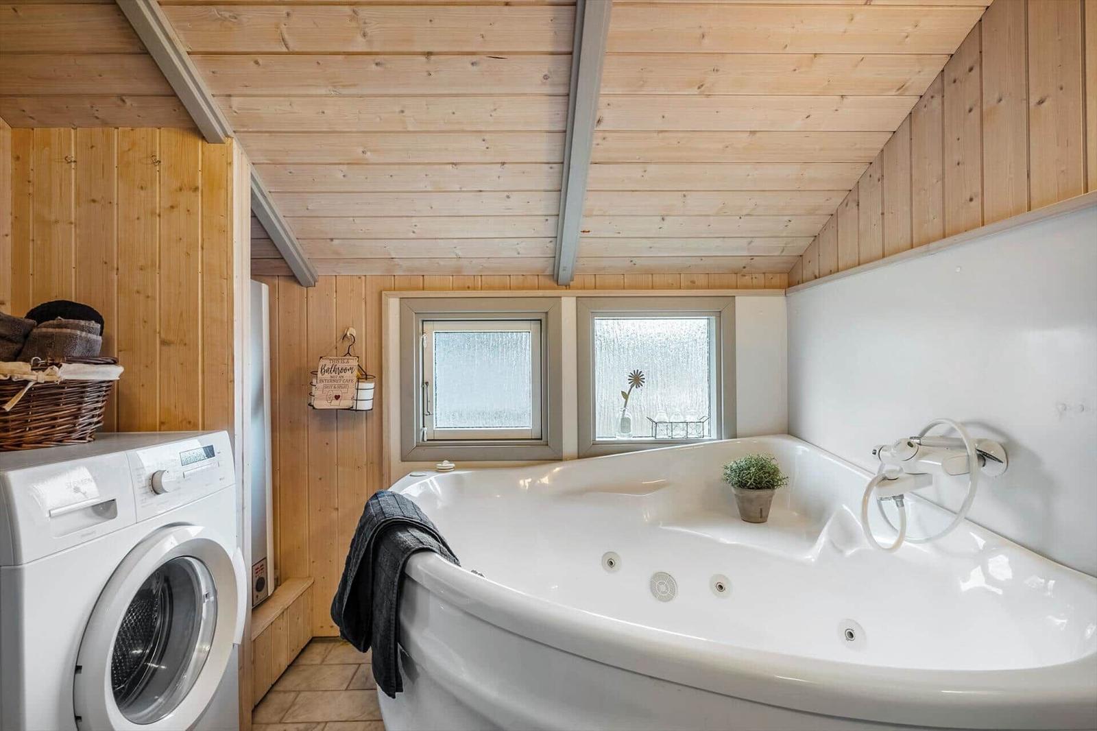 Bath with whirlpool, washing machine, and wood wall.