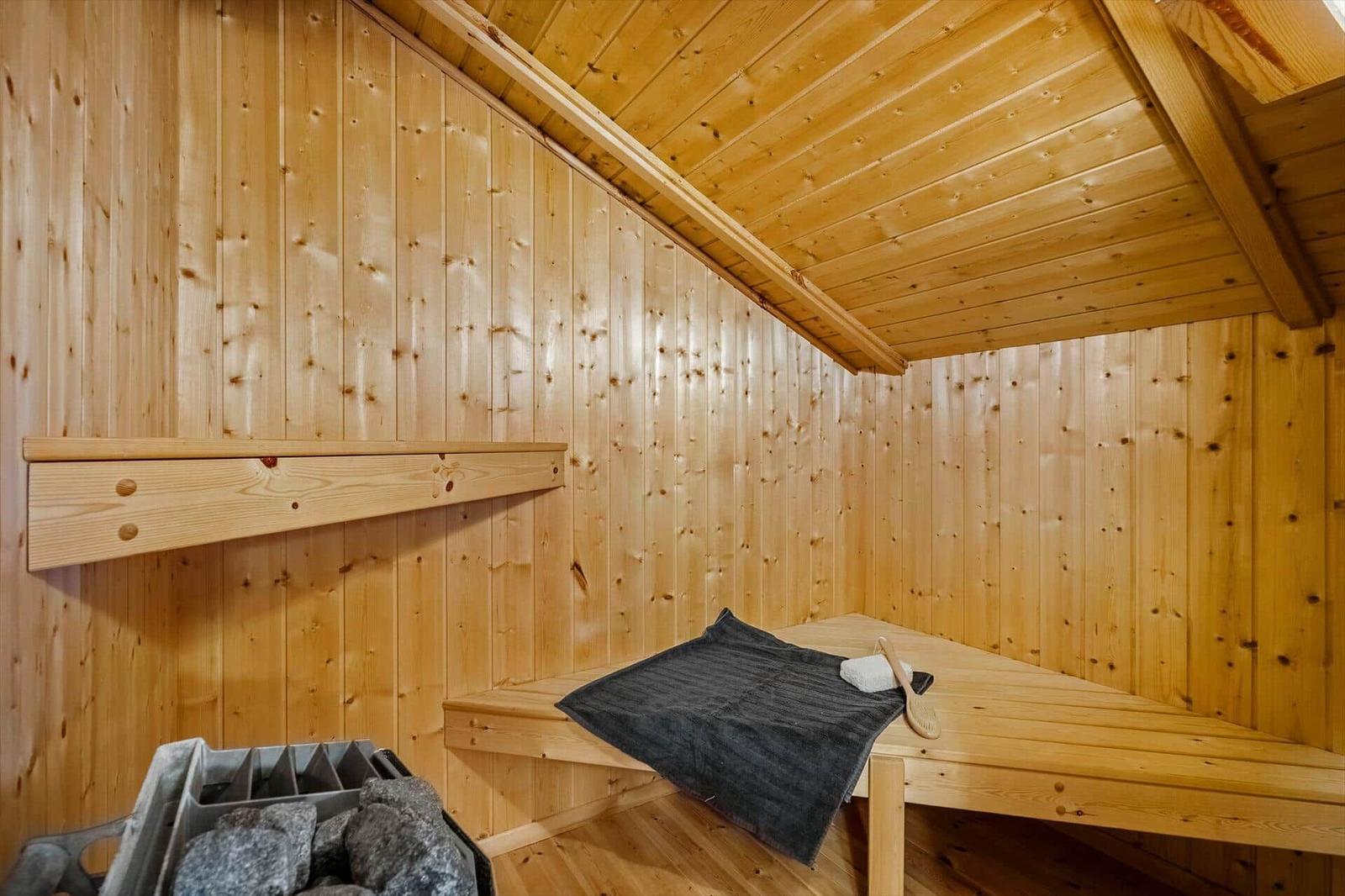 Sauna with wooden walls, bench, and stone tray