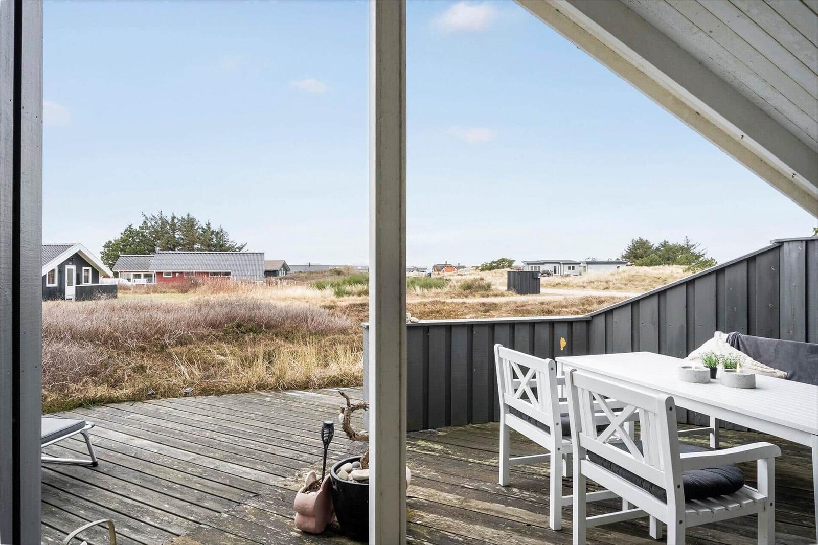 Terrace with white table and chairs, view of grassland and houses.